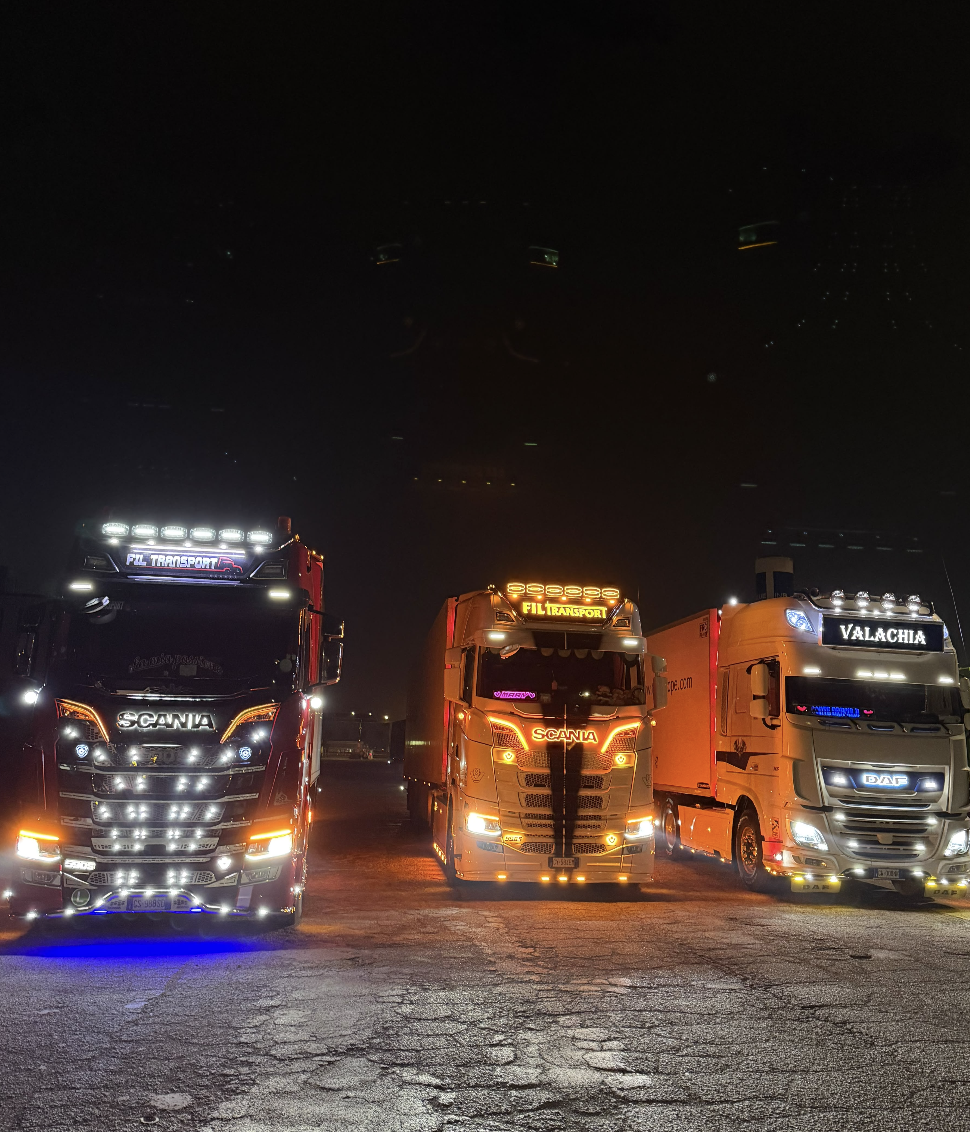 Camion in sosta di notte, con le luci dei mezzi accese