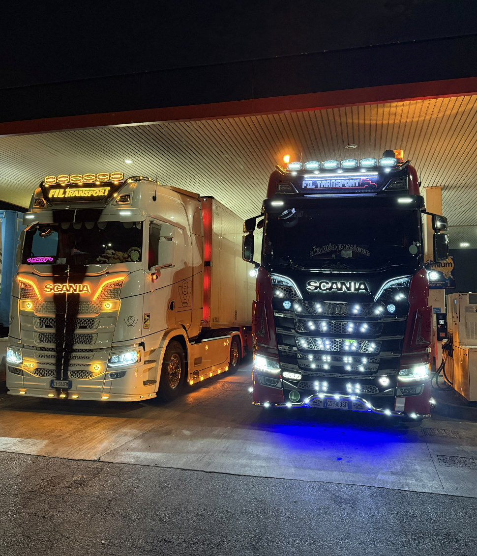 I camion della flotta FIL TRANSPORT insieme in un'area di rifornimento, di notte